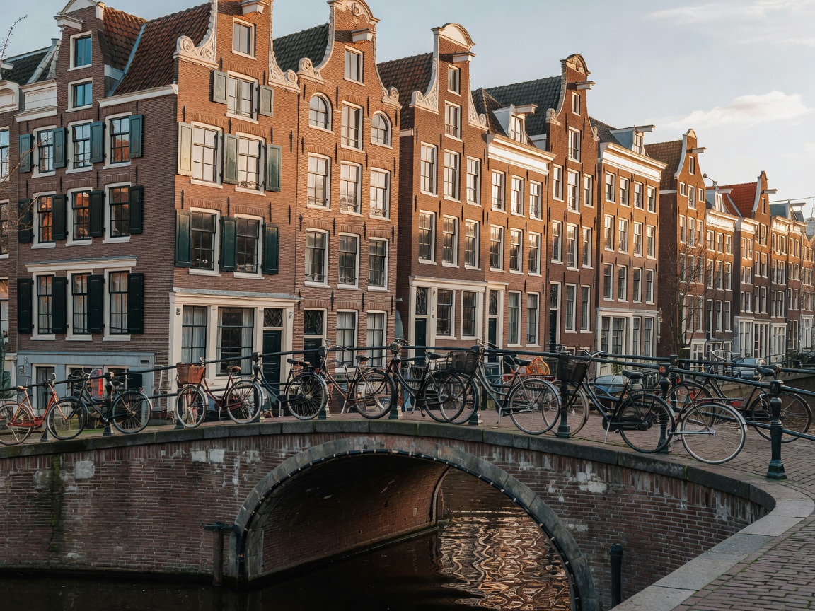 Amsterdam canal houses with bicycles along bridge railing